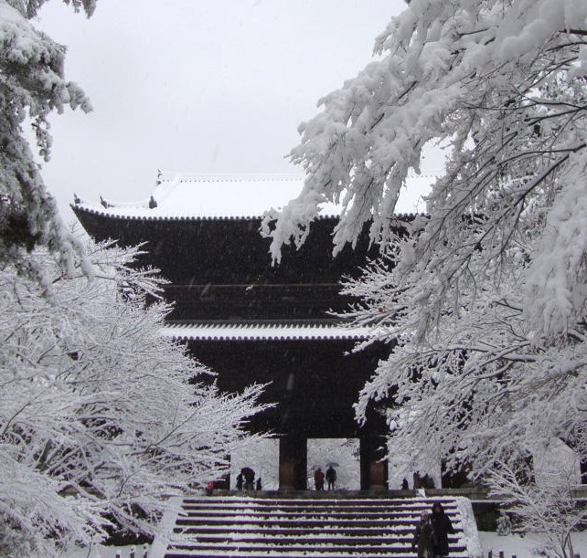 White snow covers the Sanmon entrance gate and garden trees of Nanzenji Temple, Kyoto, Japan